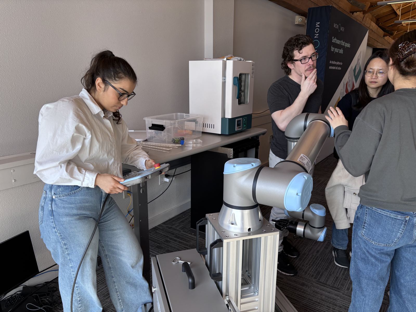 Participants setting up a robotic arm next to an incubator during the hackathon.