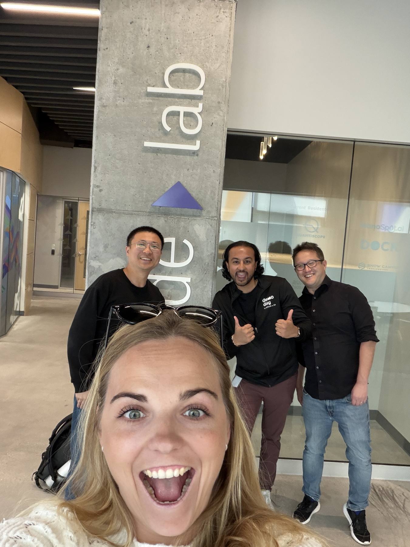 Carmen Kivisild taking a selfie with the Cypher team in the Altitude Lab lobby, under the Altitude Lab sign.