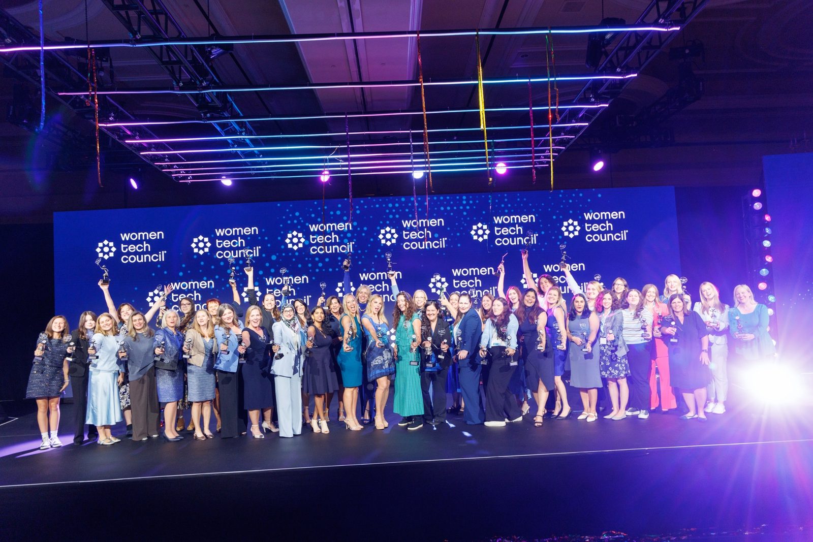 The 2026 Women Tech Awards honorees together on stage, holding their trophies up.